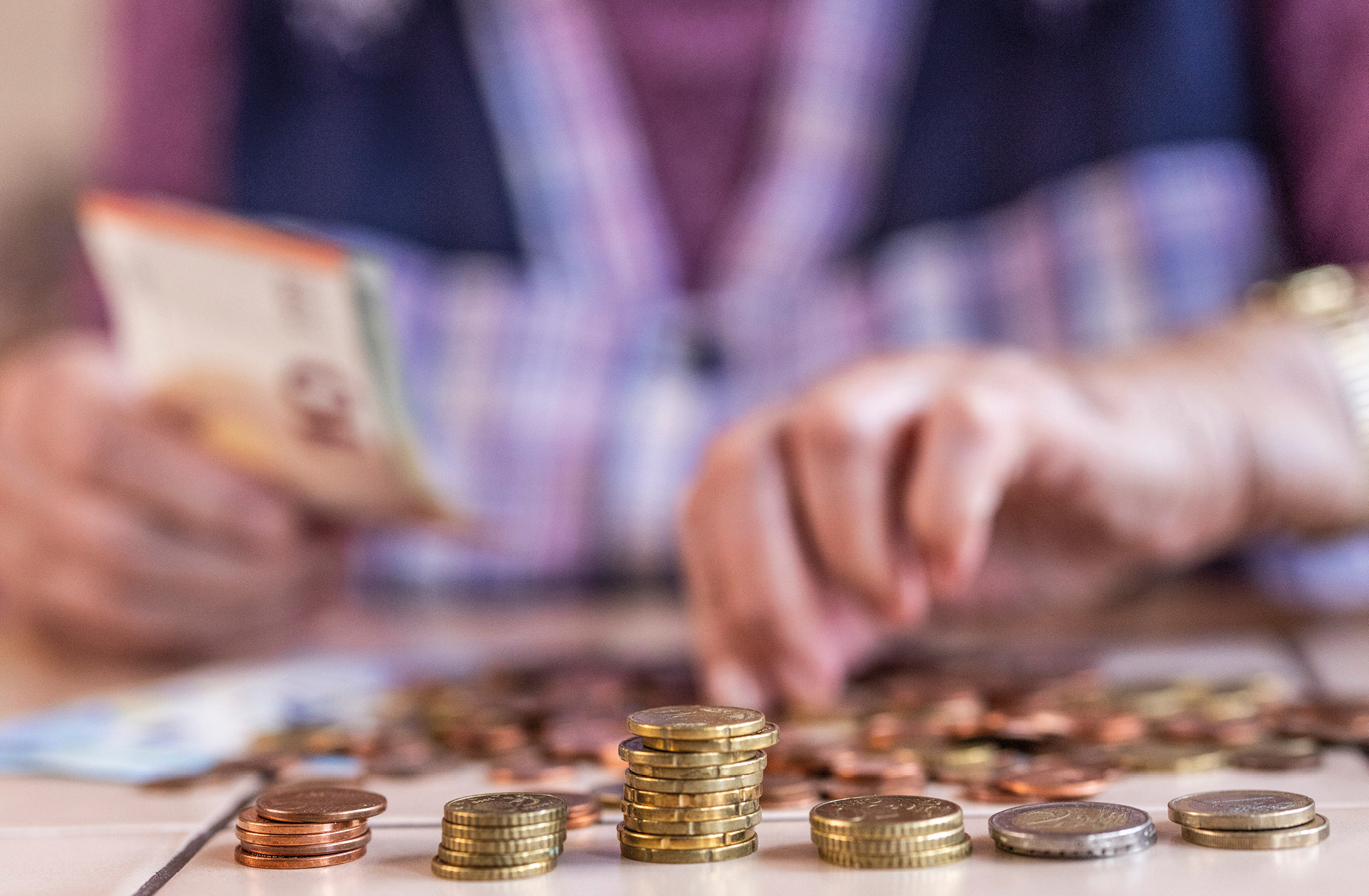 Oberkörper einer älteren Frau (ohne Kopf) die Geld zählt.