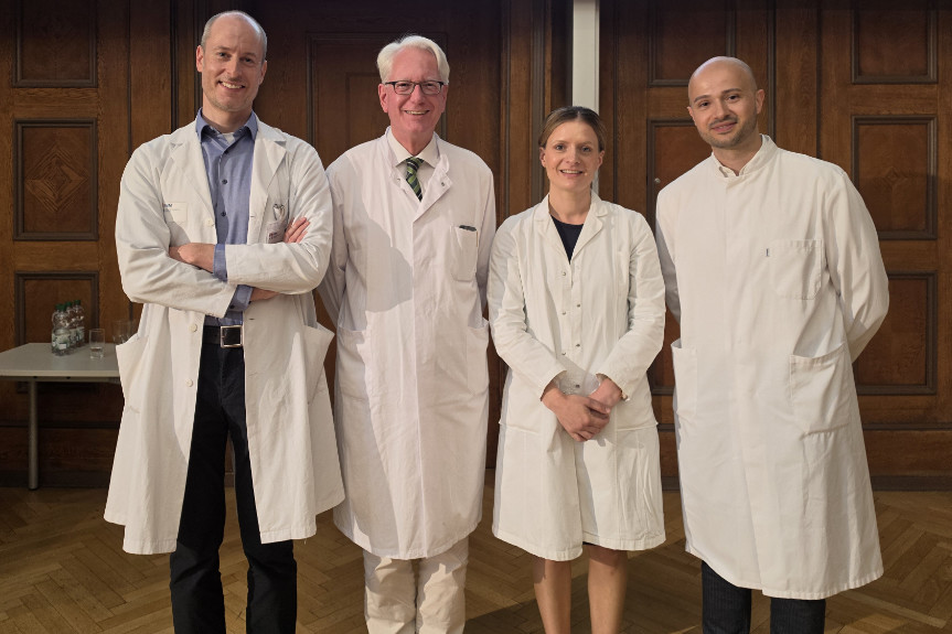 Mediziner*innen in weißen Kitteln stehen in historischem Hörsaal