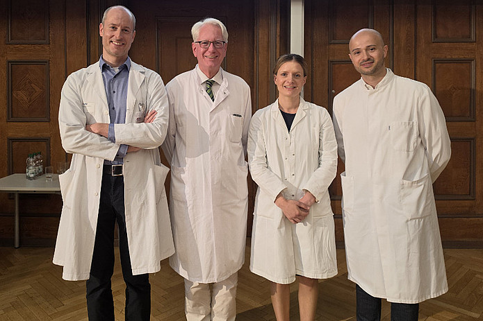 Mediziner*innen in weißen Kitteln stehen in historischem Hörsaal